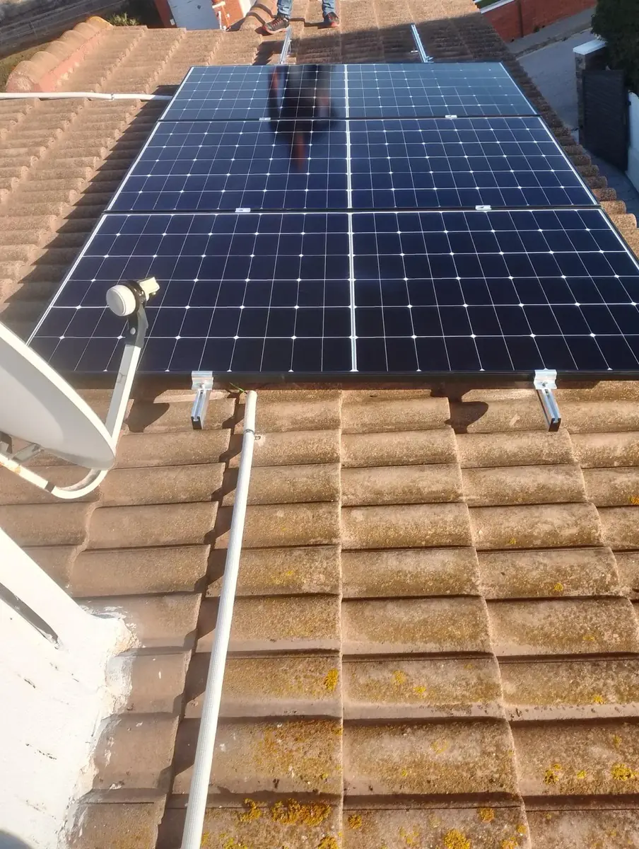 Módulos fotovoltaicos instalados sobre cubierta de teja junto a una antena parabólica