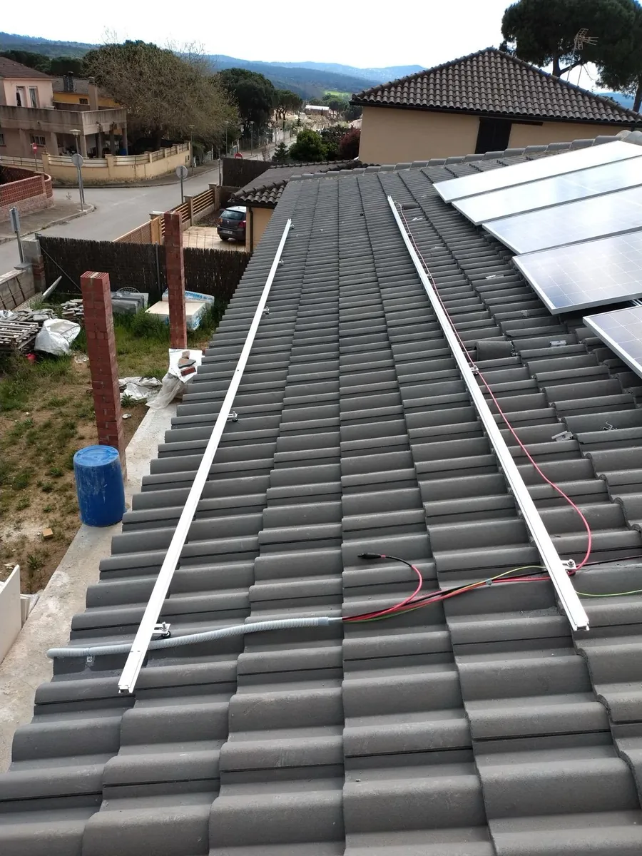 Estructura de raíles anclada sobre cubierta de teja durante el montaje de una instalación fotovoltaica