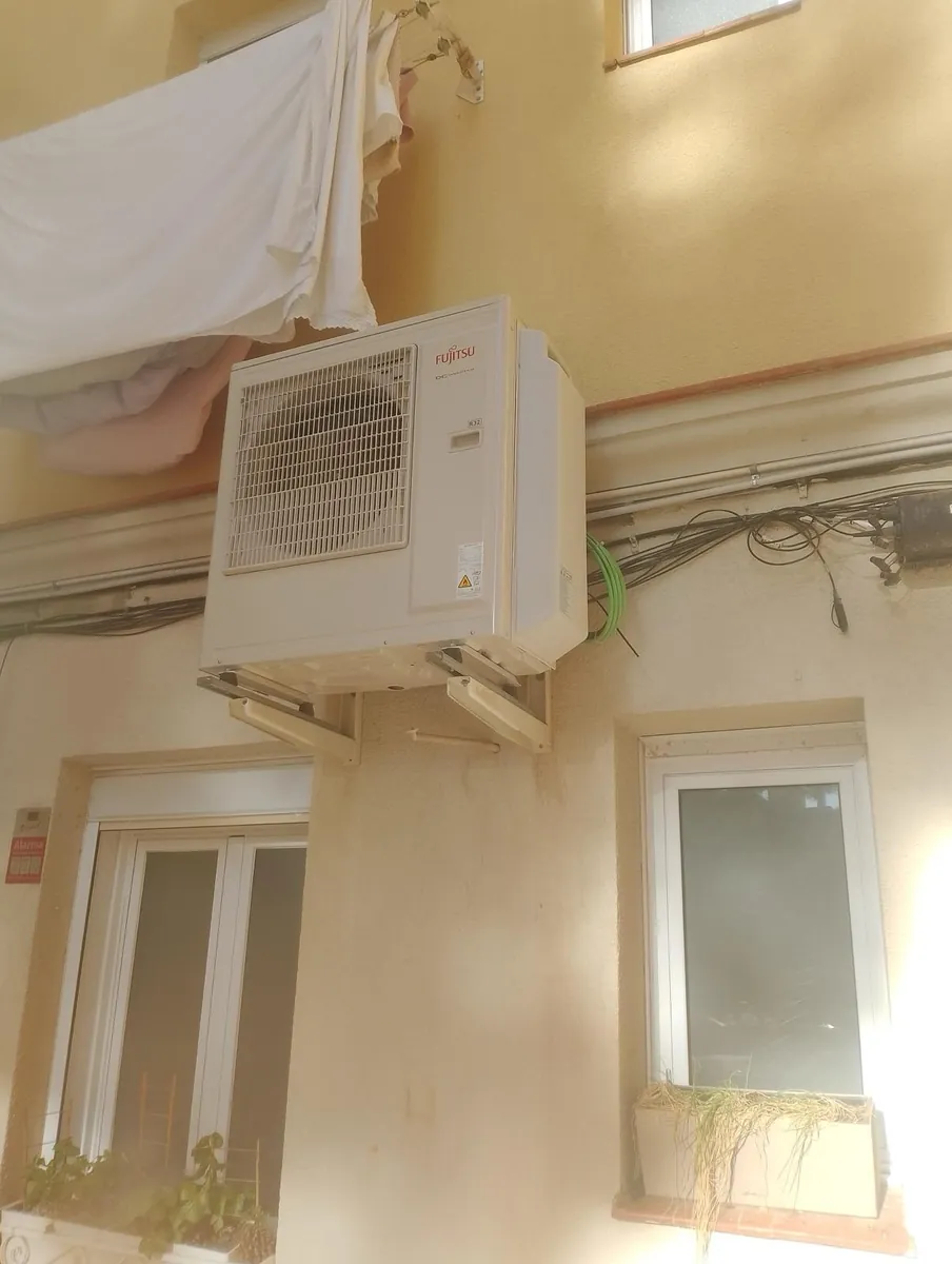 Unidad exterior de multisplit Fujitsu R-32 instalada sobre soportes en el patio interior de una finca