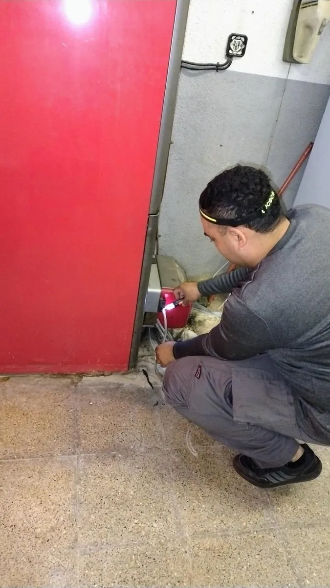Técnico revisando las conexiones de una instalación de agua caliente en un local